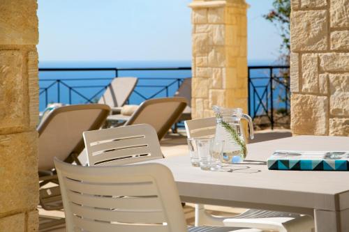 a table and chairs on a patio with a view of the ocean at Aphrodite Hills Rentals - Junior Villas in Kouklia