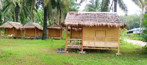 una pequeña casa con un techo de paja en la hierba en Bambu hut, en Phra Ae beach