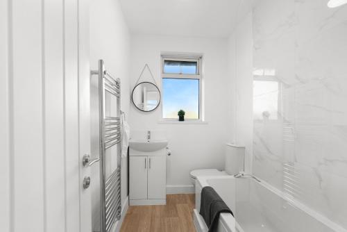 a white bathroom with a tub and a sink and a mirror at Perfect Booking 5 min Drive To Blyth Beach in Blythe