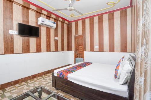 a bedroom with a bed and a tv on a wall at FabHotel Jyotish Bhawan in Ayodhya