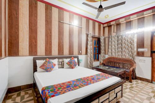 a bedroom with a bed and a chair in it at FabHotel Jyotish Bhawan in Ayodhya