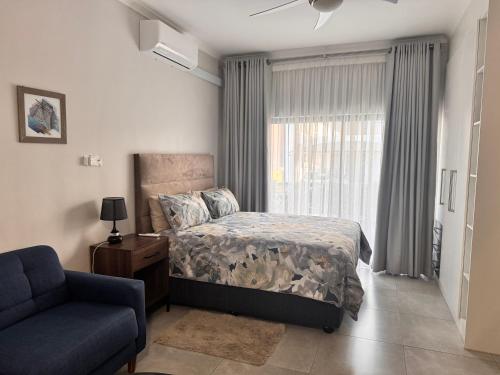 a bedroom with a bed and a chair and a window at Cozy-corner in Gaborone