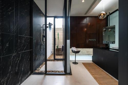 a bathroom with a shower and a glass wall at The Xcape River Kwai in Kanchanaburi