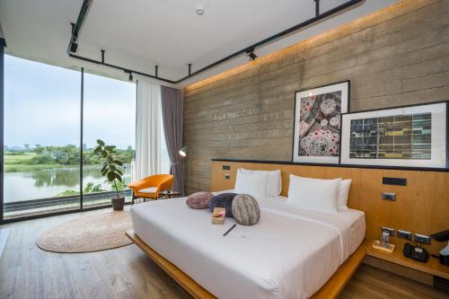 a bedroom with a large bed and large windows at The Xcape River Kwai in Kanchanaburi
