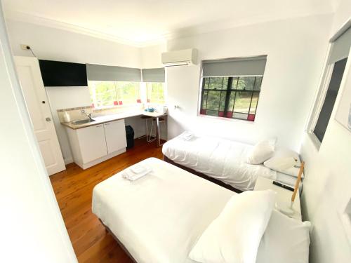 a white room with two beds and a kitchen at Royal Far West Lodge in Sydney