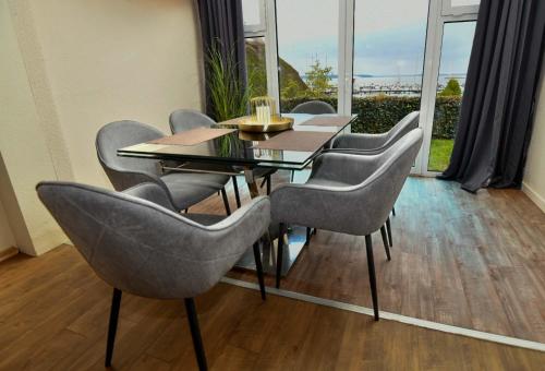 a dining room with a table and chairs and windows at Frisch renoviertes FH Südblick am Meer in Breege, Meerblick von allen drei Etagen, Terrasse, Balkon, Sauna und Parkplatz in Breege