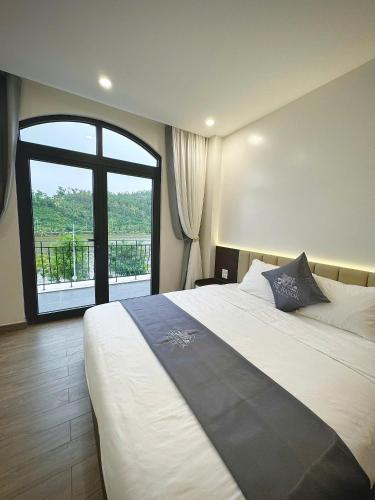 a bedroom with a large bed with a large window at The Hanok Hotel Do Son in Hai Phong