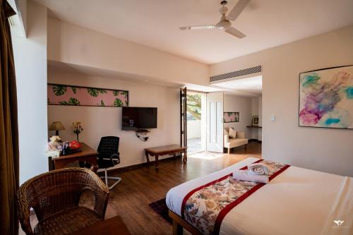 Un dormitorio con una cama, un escritorio y un televisor. en Krishna Inn - Royal Hotels, en Kolhapur