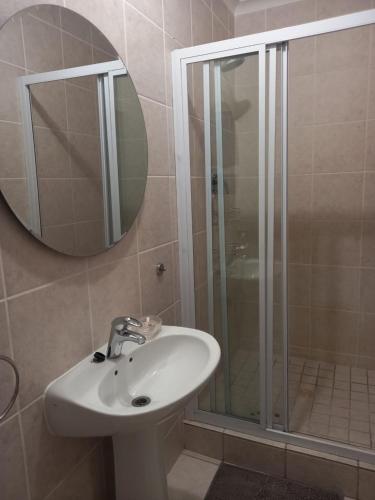 a bathroom with a sink and a shower with a mirror at Muize at Sea in Marina da Gama