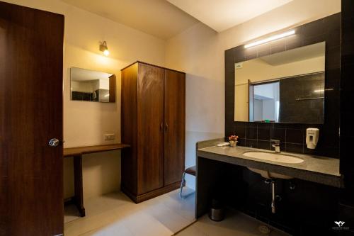 un baño con lavabo y espejo en Krishna Inn - Royal Hotels, en Kolhapur