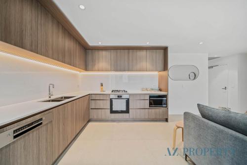 a kitchen with wooden cabinets and a couch at Brand new Luxurious 2 Bedroom Perth CBD in Perth