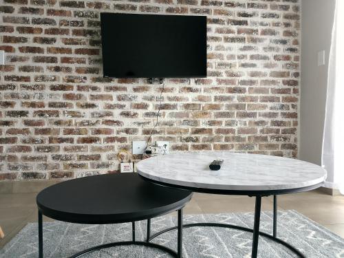 Ein Tisch mit Stuhl und Fernseher an einer Backsteinwand in der Unterkunft The Eyrie in Nelspruit