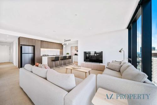 a living room with two white couches and a kitchen at Brand new Luxurious 3 Bedroom Perth CBD in Perth