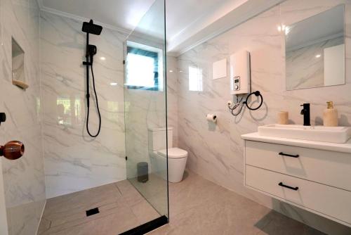 a bathroom with a shower and a toilet and a sink at Lagoon Apartments in Nuku‘alofa