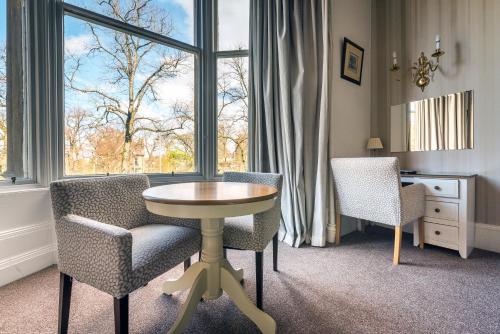 um quarto com uma mesa e cadeiras e uma janela em The Belhaven Hotel em Glasgow