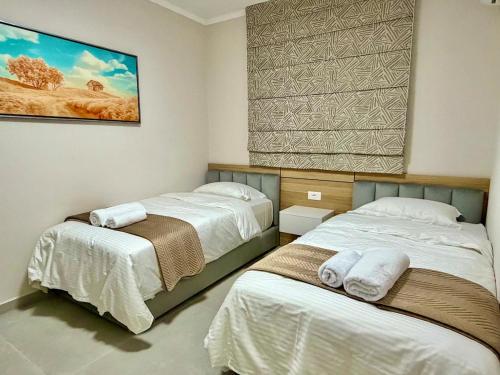 LushnjëTheGrand Stone Executive Apartment Central Lushnje的一间卧室，墙上有两张床和一幅画