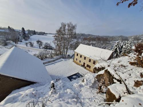 uma casa coberta de neve ao lado de um corpo de água em Chalupa Zátyní - celý objekt em Dubá