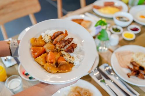 una persona sosteniendo un tazón de comida con arroz y carne en Citadines Grand Central Sri Racha, en Si Racha