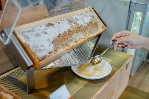Una persona está comiendo una cucharada de una colmena. en Citadines Grand Central Sri Racha, en Si Racha
