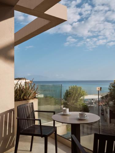 a table and chairs on a balcony with a view of the ocean at New Beach Hotel in Planos