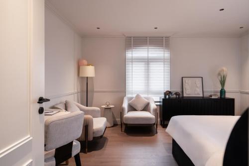 ein Hotelzimmer mit einem Bett und Stühlen und einem Fenster in der Unterkunft AMANA Boutique Hotel - Thân Văn Nhiếp in Ho-Chi-Minh-Stadt