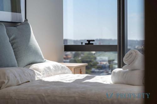 a bed with a teddy bear sitting on it in front of a window at Brand new Luxurious 1 Bedroom Perth CBD in Perth