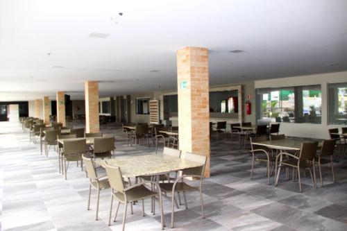 una sala da pranzo con tavoli, sedie, tavoli e sedie e una sedia a sdraio di Park Veredas Flat 310 Premium a Rio Quente
