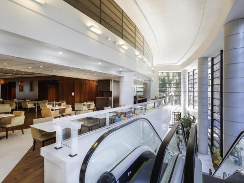um átrio com uma cafetaria com mesas e cadeiras em Mercure Sao Paulo Grand Plaza Paulista em São Paulo