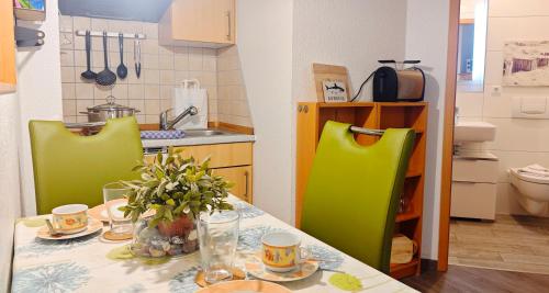 a kitchen with a table and two green chairs at Ferienwohnung Ostseeblick in Breege