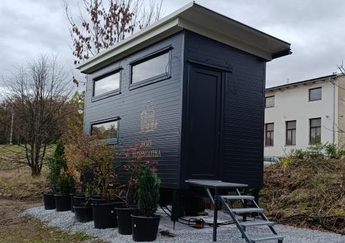 a black tiny house with a ladder and plants at Boží maringotka in Humpolec