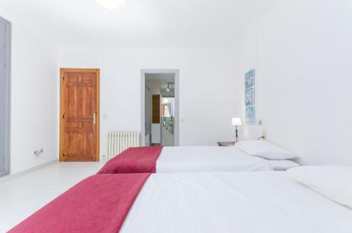a white bedroom with two beds and a wooden door at YourHouse Can Marques villa in Palma de Mallorca