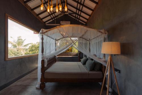 Villa Sri Ceylon في Habaraduwa Central: غرفة نوم بها سرير مظلة مع مصباح ونافذة