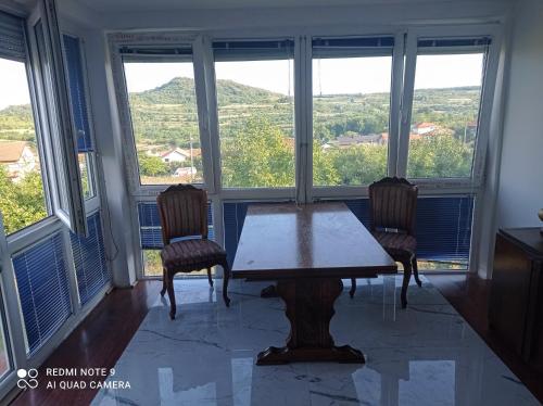 Una mesa y dos sillas en una habitación con ventanas. en Sunny Villa, en Belgrado