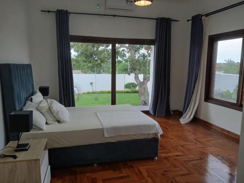 a bedroom with a bed and a large window at Ntsudini 2 in Marracuene