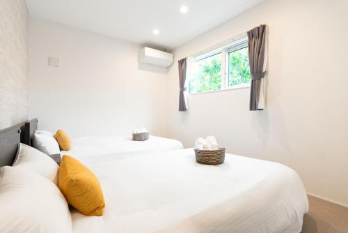 2 weiße Betten in einem Zimmer mit Fenster in der Unterkunft Grandioso Okinawa Pool Villa Onna - Vacation STAY 52628v in Inbu