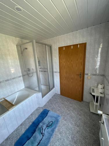 a bathroom with a tub and a shower and a blue rug at Ferienwohnung Furchner in Sayda