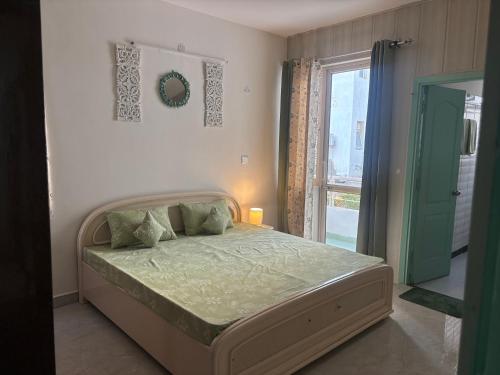 The Green Door في Lāndrān: غرفة نوم مع سرير مع لحاف أخضر ونافذة