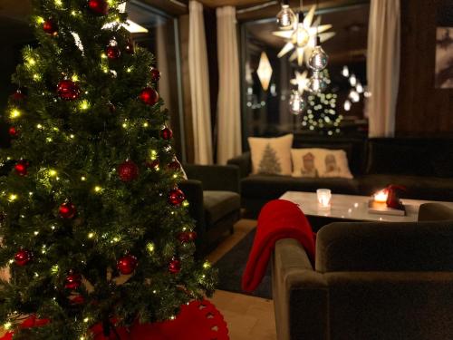 ein Weihnachtsbaum im Wohnzimmer mit Sofa in der Unterkunft Christmas-decorated mountain cabin - panoramic view! in Torvetjørn