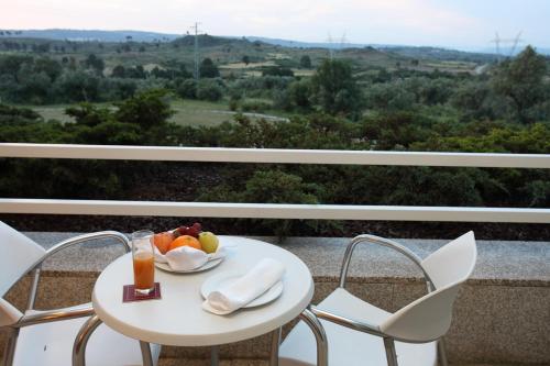 a table with a plate of fruit and juice on a balcony at INATEL Vila Ruiva in Vila Ruiva