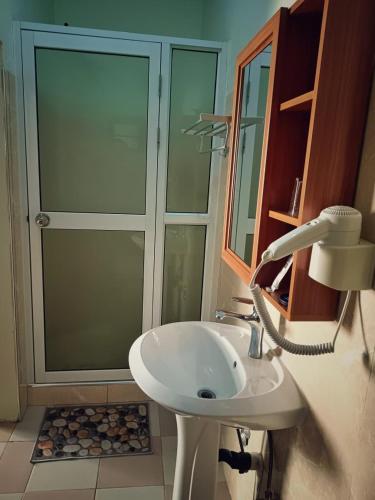 a bathroom with a shower and a white sink at Hotel Bom Amigo in Inhambane