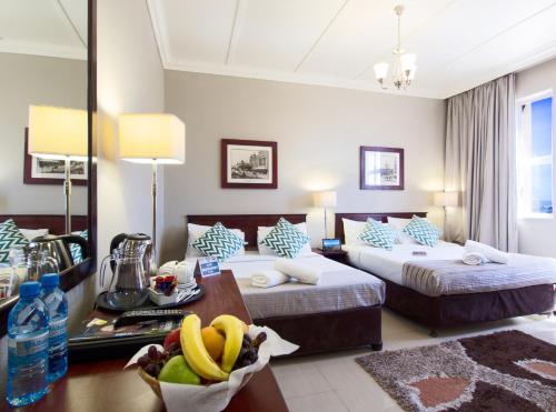 ein Hotelzimmer mit zwei Betten und einem Tisch mit Bananen darauf in der Unterkunft Albany Hotel in Durban