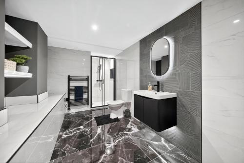 a bathroom with a sink and a toilet and a mirror at Rosemont ApartHotel in Leeds