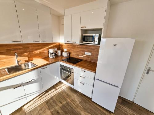 eine Küche mit weißen Schränken und einer Spüle und einer Mikrowelle in der Unterkunft Maison - Saint-Martin La Plaine - Loire in Saint-Martin-la-Plaine