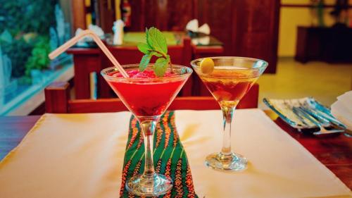 イニャンバネにあるHotel Bom Amigoのカクテル2杯をテーブルの上で楽しめます。