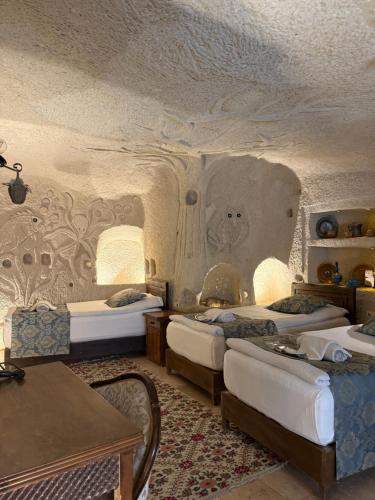 a room with three beds and a table in a room at Arif Cave Hotel in Göreme