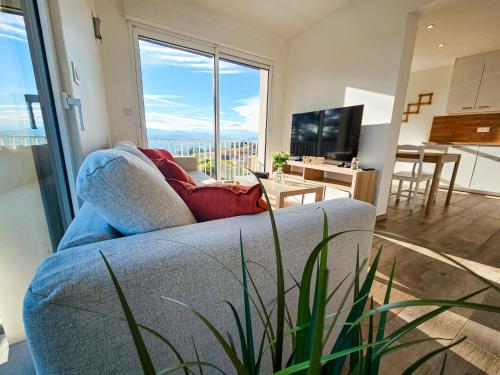 ein Wohnzimmer mit Couch und großem Fenster in der Unterkunft Maison - Saint-Martin La Plaine - Loire in Saint-Martin-la-Plaine