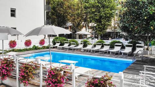 a swimming pool with chairs and umbrellas and a pool at Hotel Riz in Cesenatico