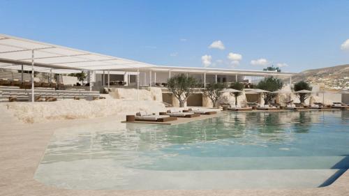 ein Swimmingpool mit Liegestühlen und ein Gebäude in der Unterkunft Kenshō Paros in Krotiri