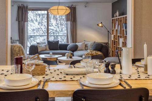 een woonkamer met een tafel met borden en wijnglazen bij AO HOUSE - Chalet PAN BENA in Les Houches
