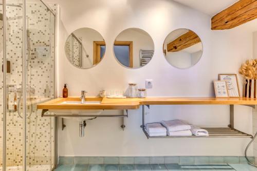 La salle de bains est pourvue d'un lavabo et de miroirs. dans l'établissement AO HOUSE - Chalet PAN BENA, aux Houches